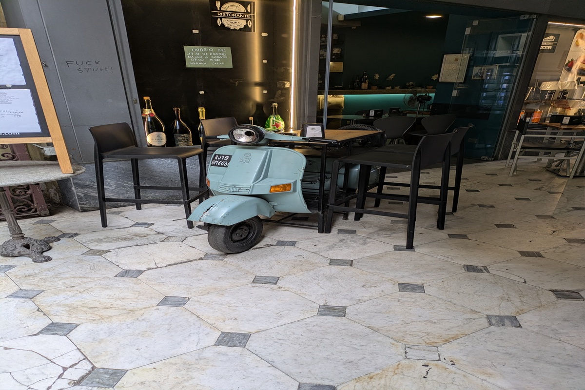 storytelling aziendale, vecchia Vespa parcheggiata dentro un bar dal pavimento in marmo a ottagoni